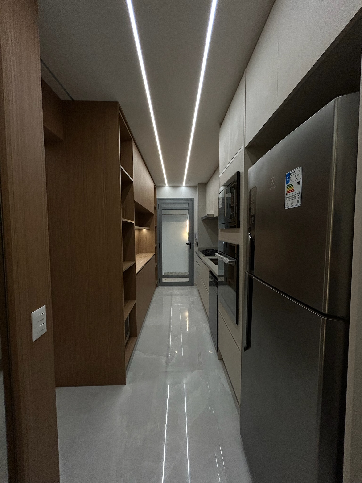 Cozinha com marcenaria em madeira e iluminação linear LED