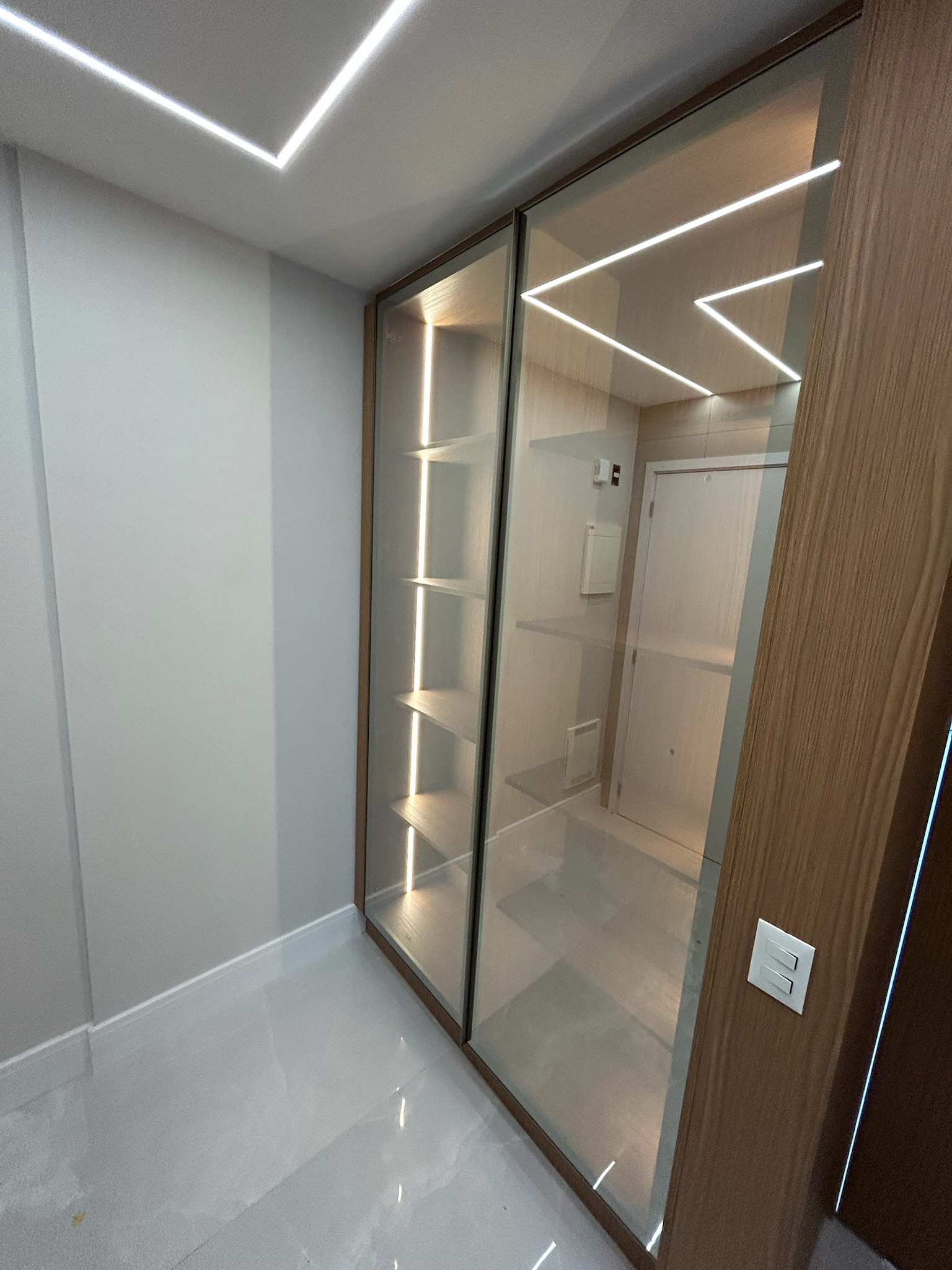 Closet planejado com portas de vidro e iluminação LED