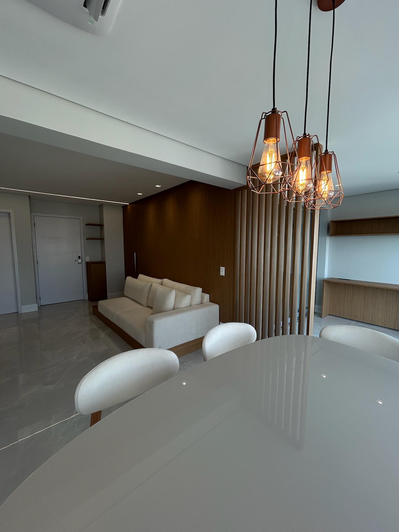 Sala de jantar com pendentes cobre e painel de madeira